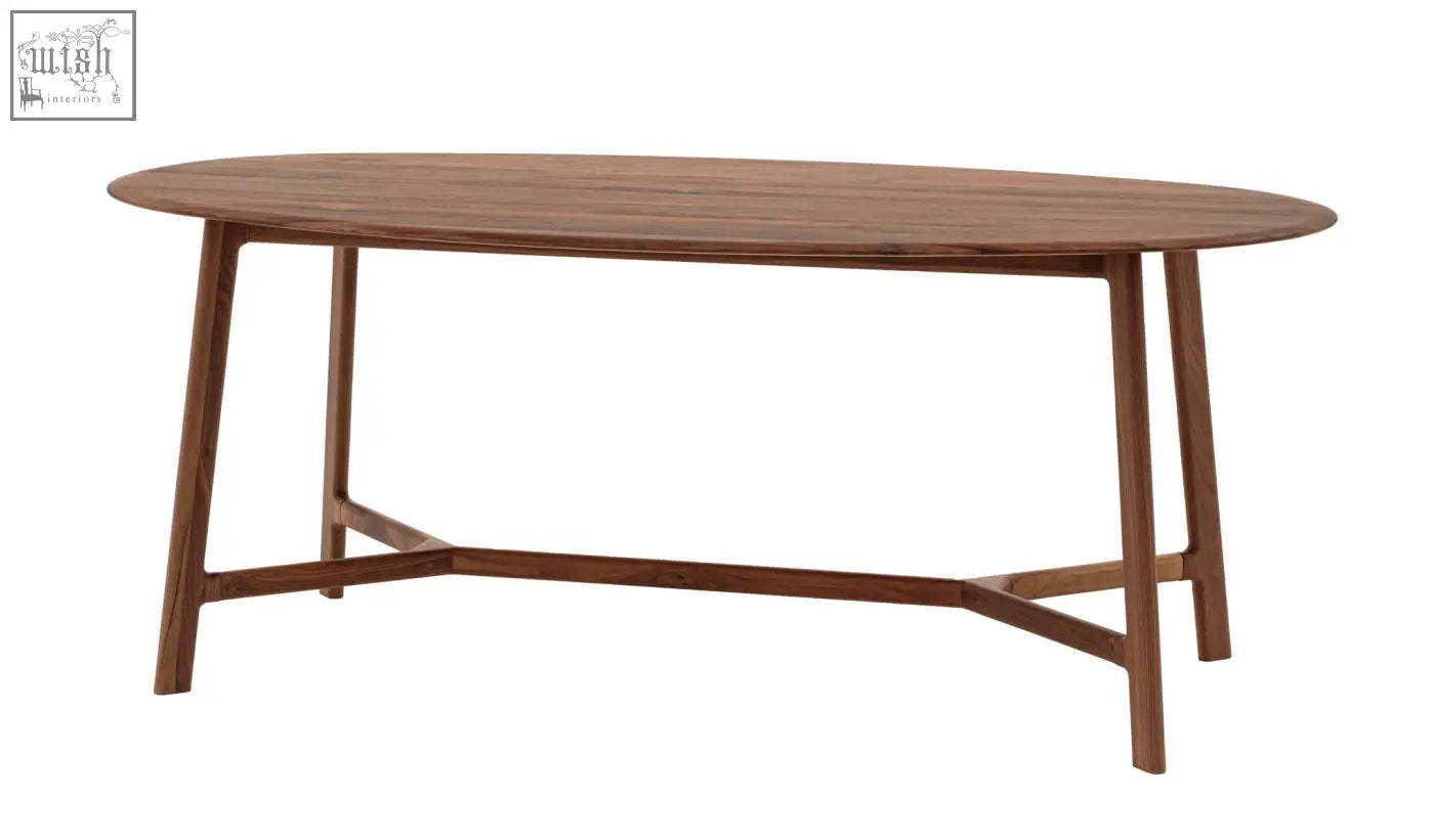 The med dining table walnut features a solid walnut oval top with soft edges and tapered legs connected by a stretcher