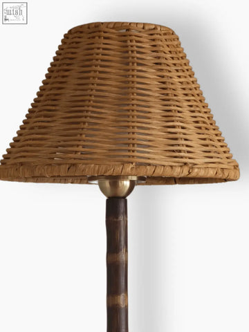 The raffles lamp features a natural woven wicker lampshade with a tapered shape and a solid brass base made from responsibly sourced bamboo