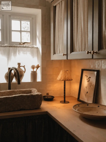 The raffles lamp features a stone sink with a rustic textured surface and dark metal faucet on a solid brass base
