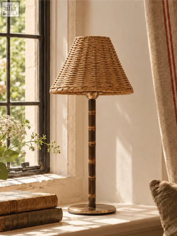 The raffles cordless bamboo lamp features a woven rattan shade with a solid brass base and responsibly sourced bamboo accents