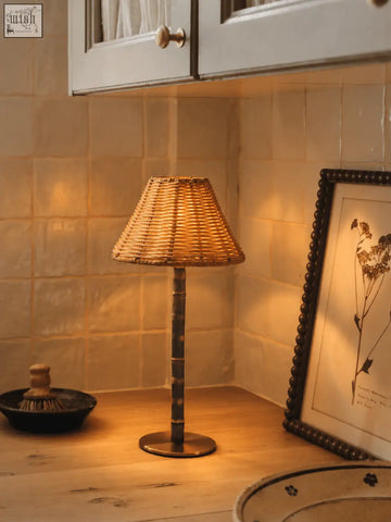 Woven wicker raffles lamp with a dark solid brass base made of responsibly sourced bamboo cordless design