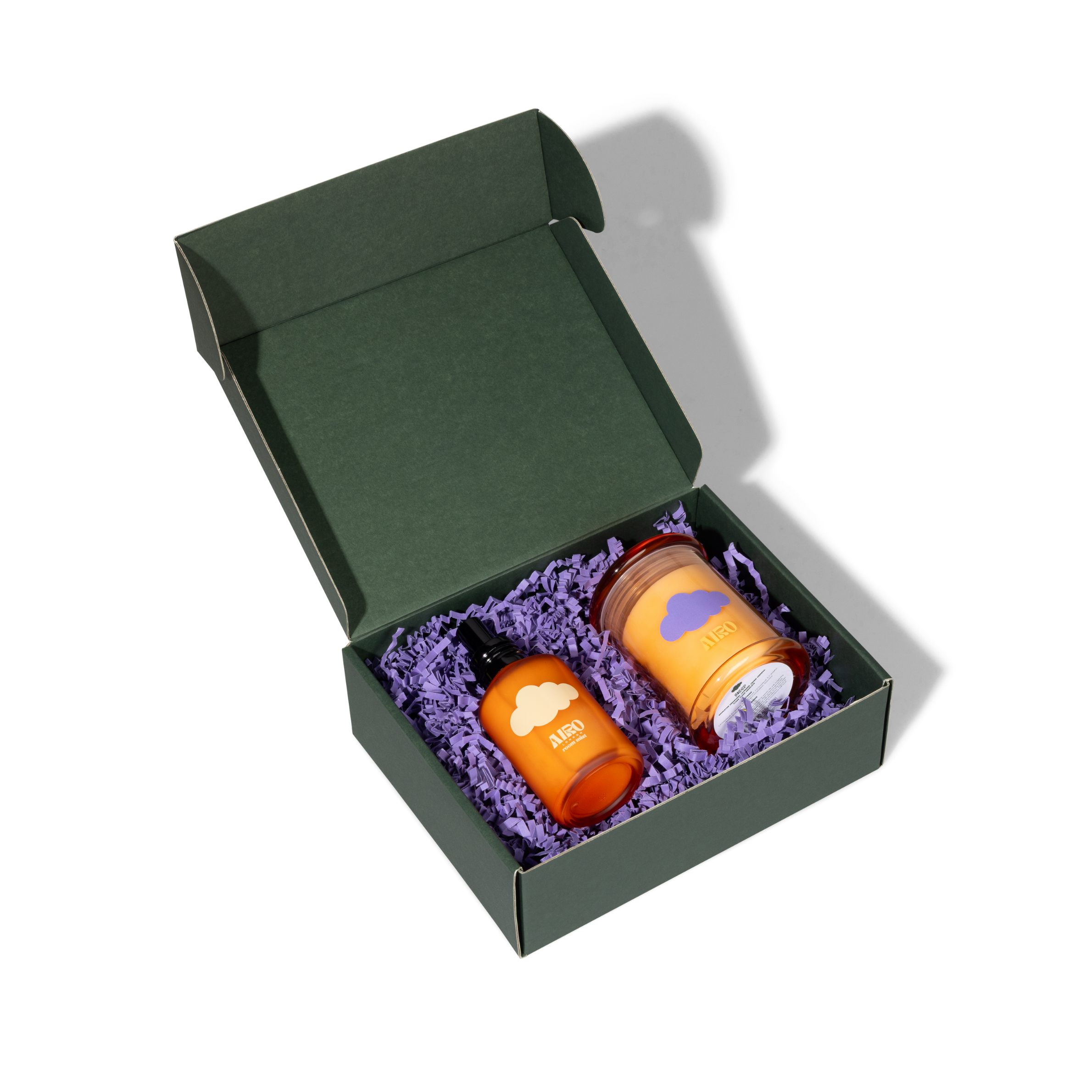 Orange glass sleep mini candle bottle with white cloud design and black dropper cap in dark green gift box with purple paper