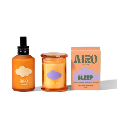 Orange glass jar with yellow sleep mini candle featuring a purple cloud design from the relaxation gift set