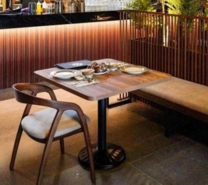 Wooden table with dark brown finish and black metal pedestal base shown with the scandi arm chair