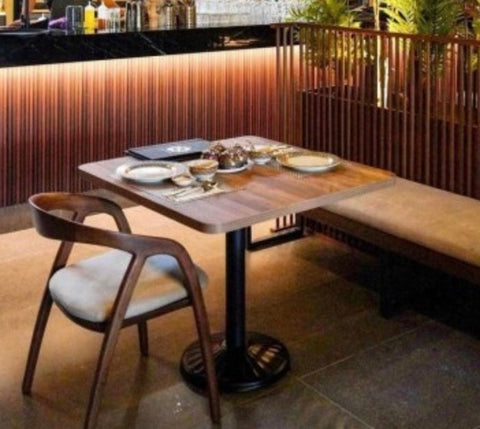 Wooden table with dark brown finish and black metal pedestal base shown with the scandi arm chair