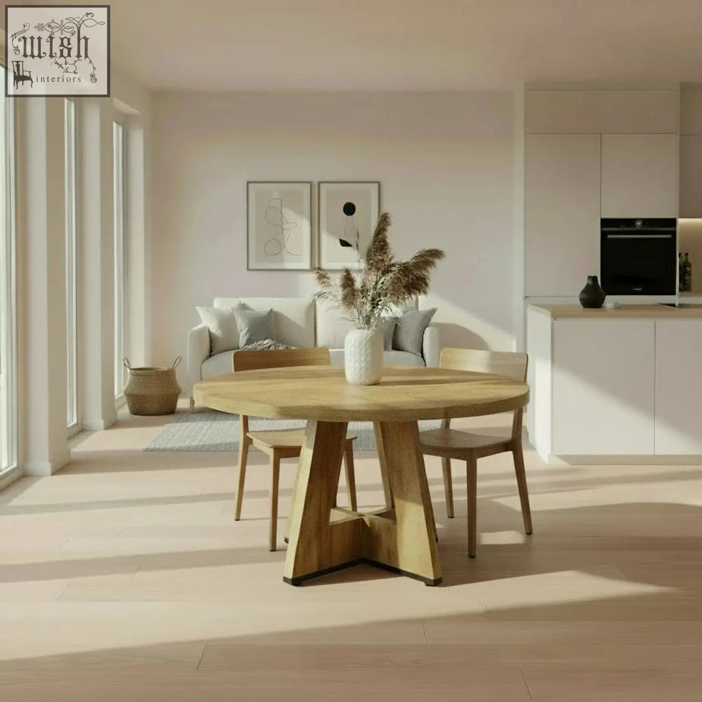 The somerset round oak dining table features a light wood pedestal base with a vase of dried pampas grass on top