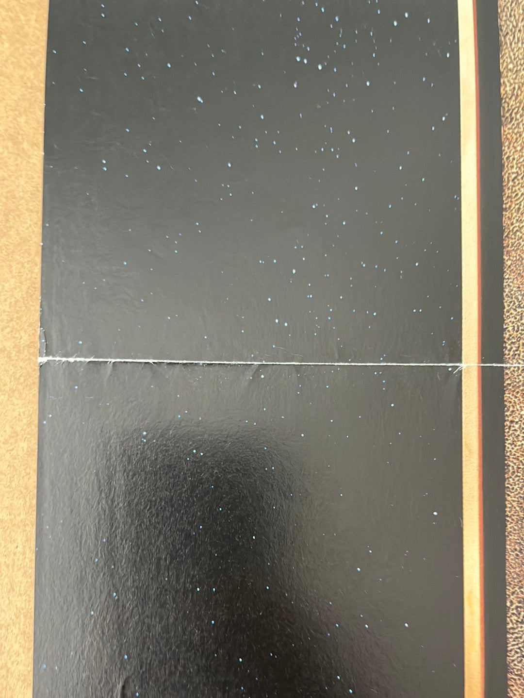 A black starry surface panel with glittery specks and seam from the star wars trilogy french petite cinema poster