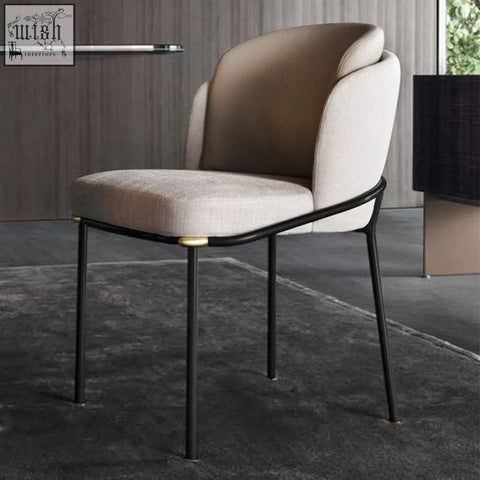 Beige upholstered theobald dining chair with sleek black metal frame and gold toned accents for dining room use