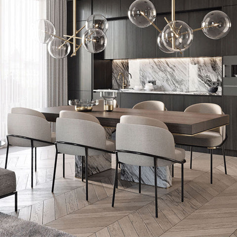 Modern dining table with a sleek wooden top and marble base surrounded by upholstered theobald dining chairs