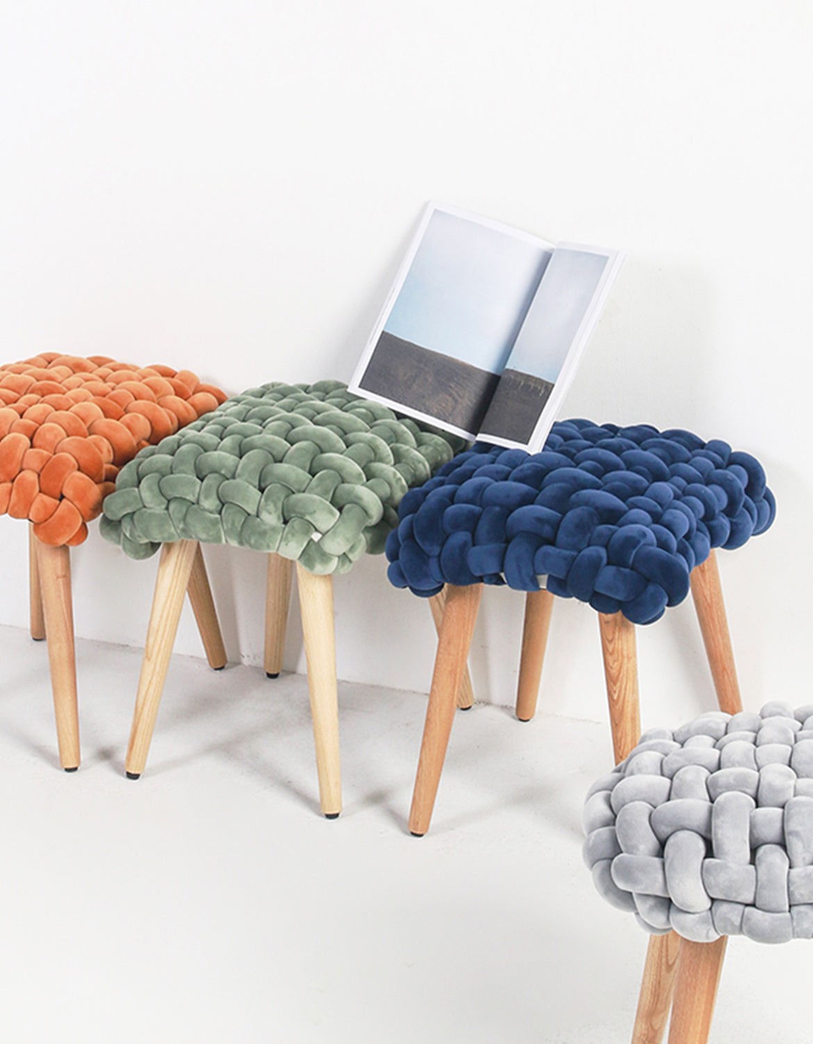 Thick knot dressing table stool with vibrant orange knitted cushion and light wood legs for a cozy knot dressing area