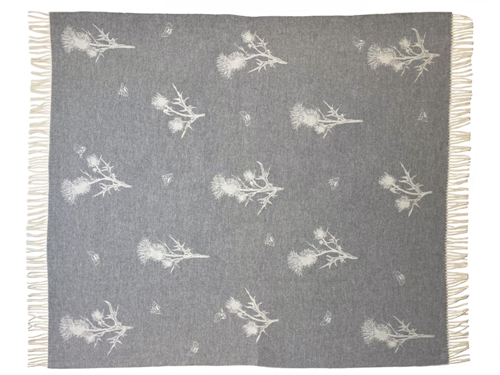 Gray merino lambswool throw blanket with white thistle and bee patterns and fringed edges for cozy use