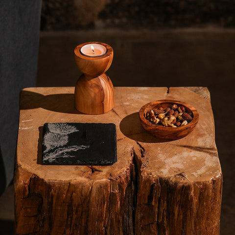 A warm-toned wooden candle holder with polished finish and natural wood grain paired with thistle single slate coaster