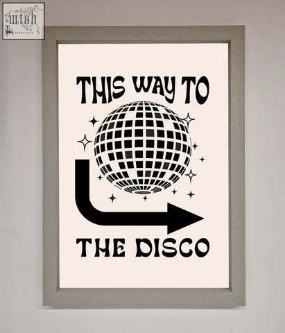A black and white disco framed poster with a disco ball and arrow design saying this way to the disco in a frame