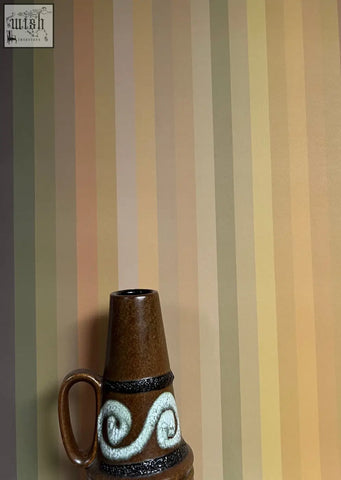 Brown ceramic vase with handle and white swirling patterns complementing tonal stripe wallpaper ochre colour ways