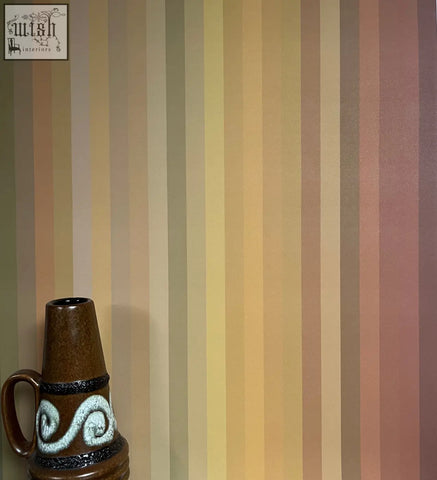 Brown ceramic vase with white swirling pattern and black bands complements tonal stripe wallpaper ochre colour ways