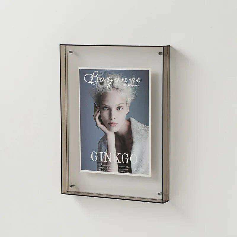 Transparent acrylic picture frame with matte metal border designed as a wall-mounted magazine display rack