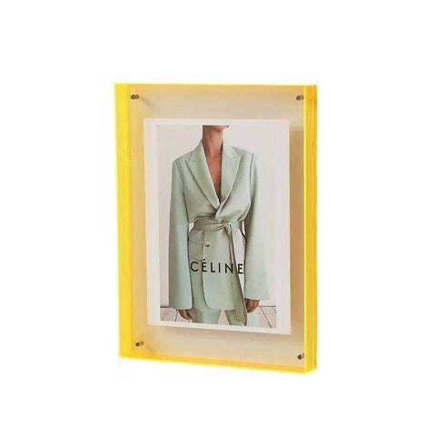 Vibrant yellow acrylic picture frame with transparent acrylic material holding a light green celine suit print
