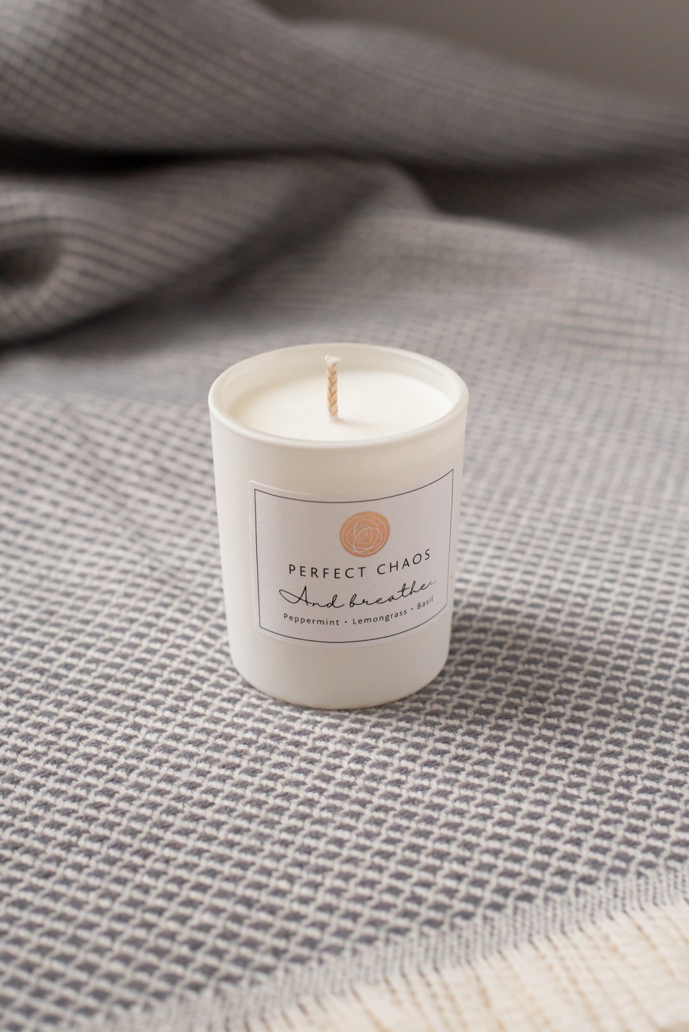 White cylindrical travel candle with peppermint lemongrass basil essential oils and minimalist perfect chaos and breathe label