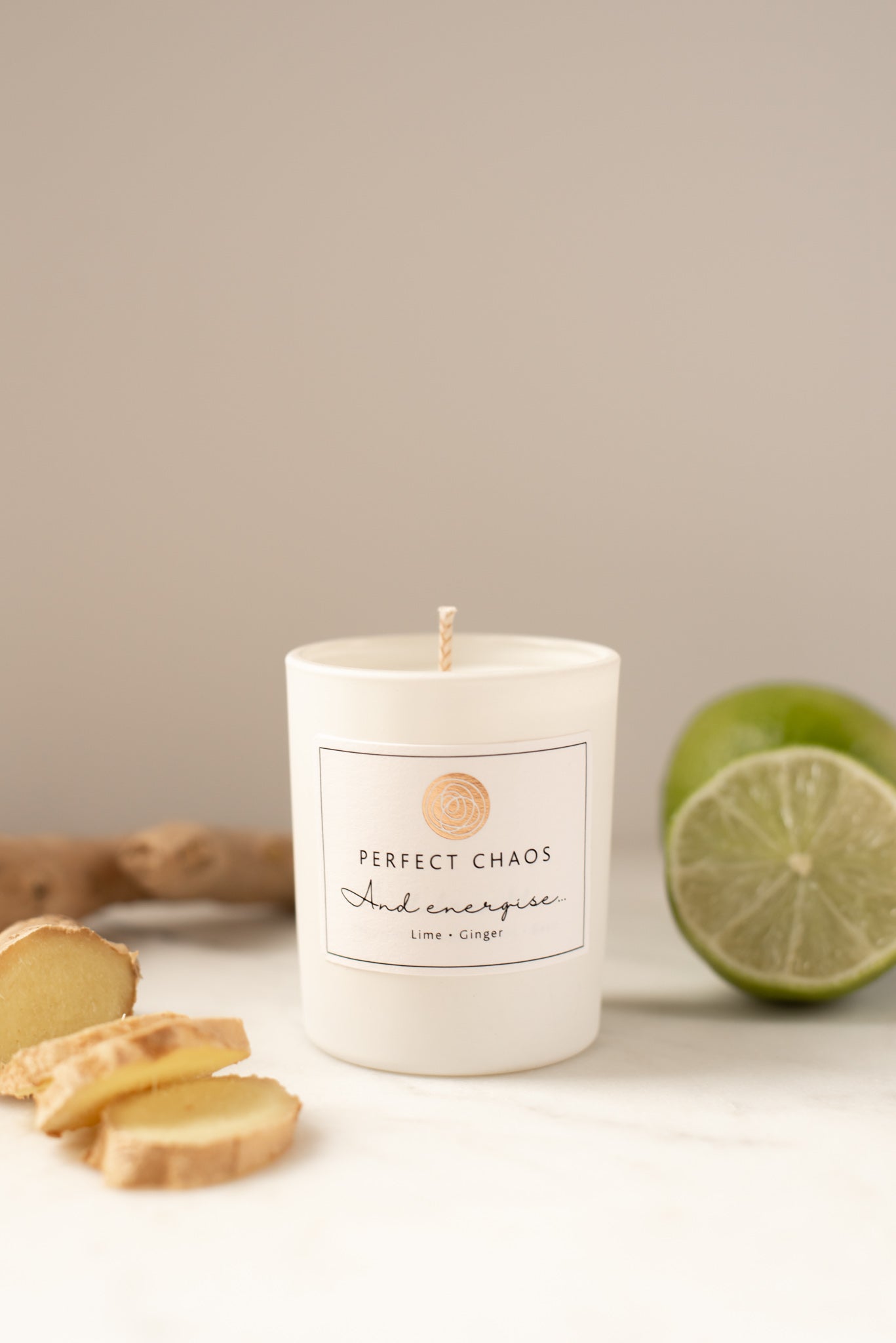 White cylindrical travel candle with energise lime and ginger scent and minimalist perfect chaos label
