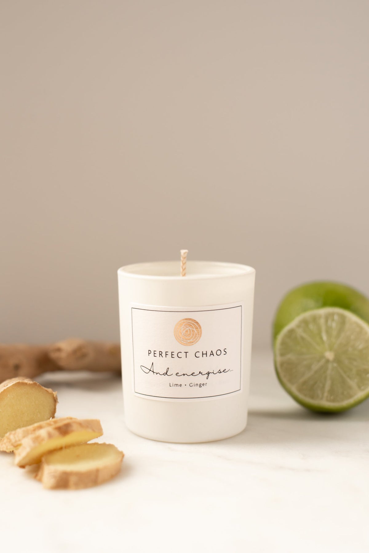 White cylindrical travel candle with energise lime and ginger scent and minimalist perfect chaos label