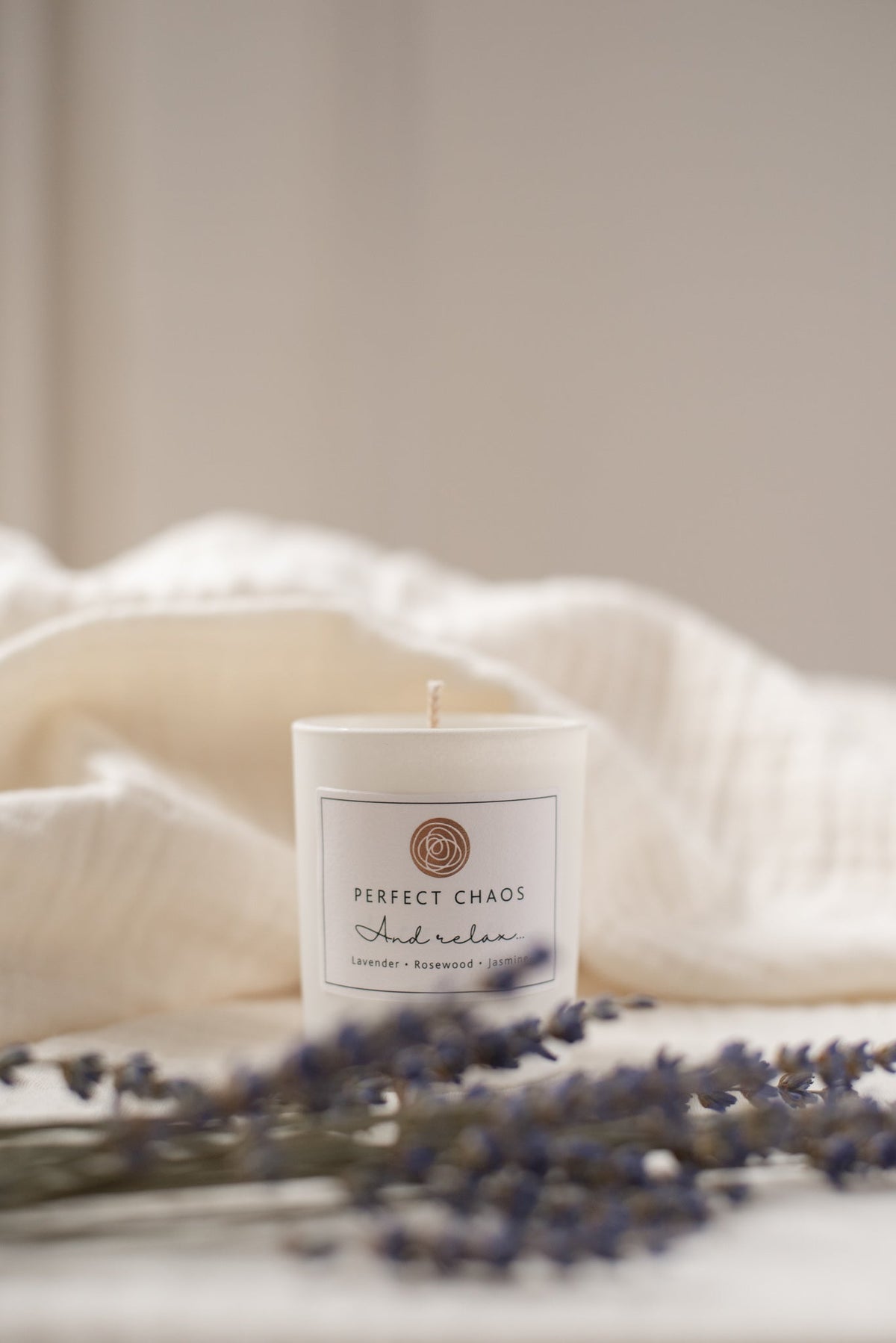 White cylindrical travel candle with a minimalist label perfect chaos and relax lavender and rosewood scent
