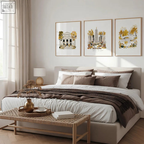 A golden metallic vase with textured surface sits on a woven tray next to travel poster art prints of empire state view