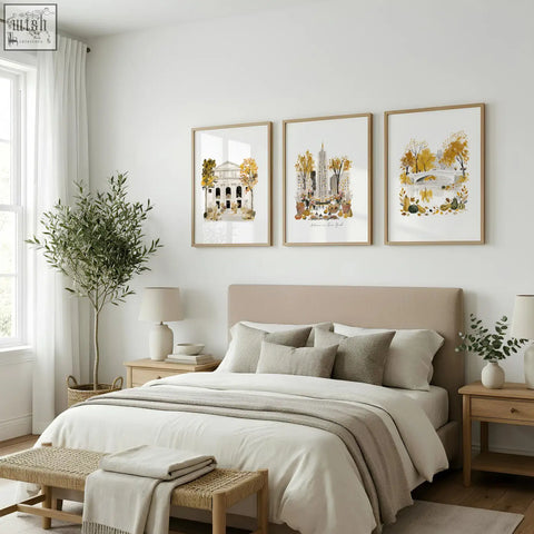 Beige upholstered bed with matching pillows and neutral throw blanket next to travel poster art prints featuring empire state