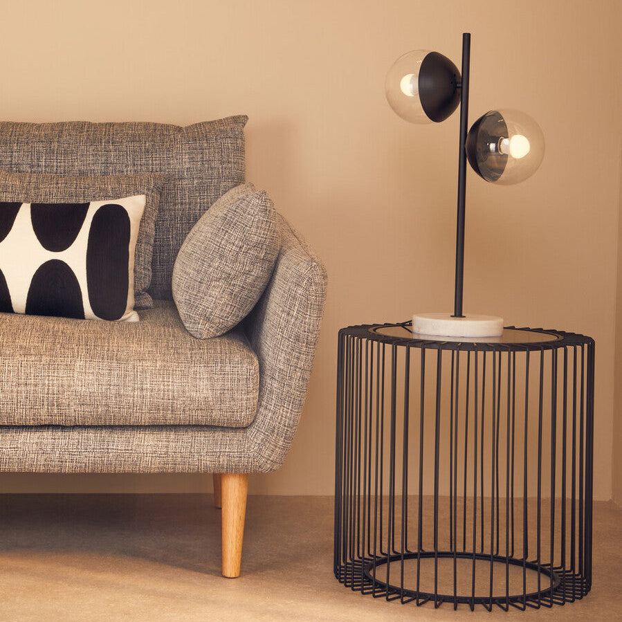 Modern black metal table lamp with two glass shades and white marble base on black metal round side table with glass top