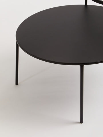 Black round trento coffee table with glass and metal tops and slender metal legs for lower level use