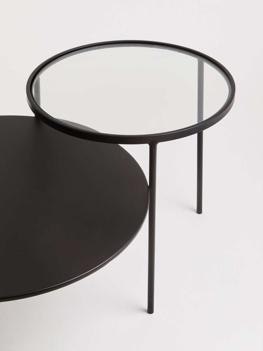 Black round trento coffee table with glass top and minimalist metal frame for lower level living spaces