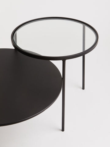 Black round trento coffee table with glass top and minimalist metal frame for lower level living spaces