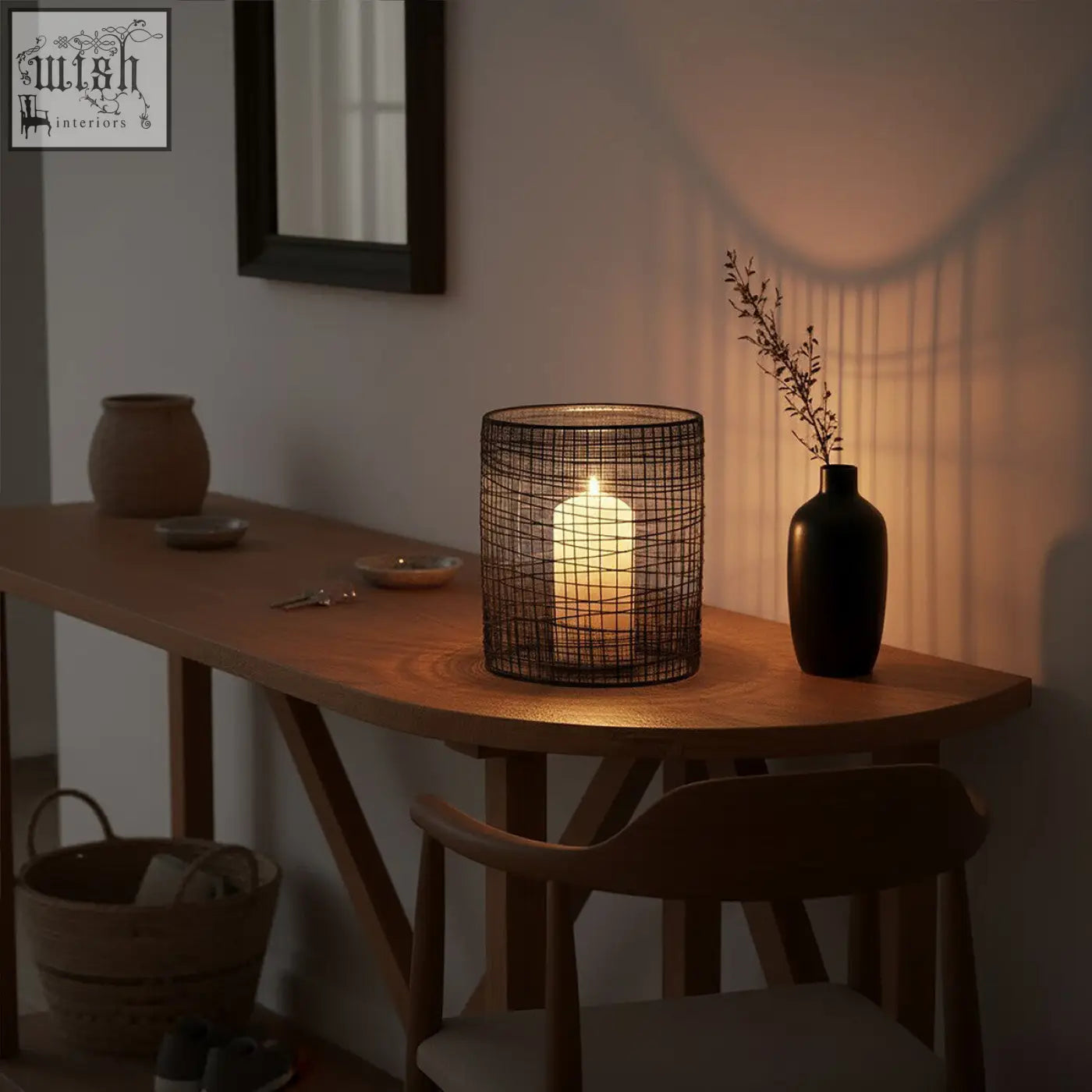 Black wire mesh trento cylindrical lantern with glowing white pillar candle inside for cozy lighting