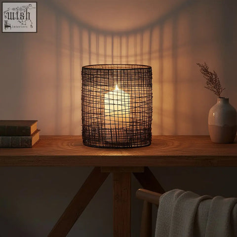 Black woven wire trento cylindrical lantern with glowing white candle inside for cozy ambient lighting