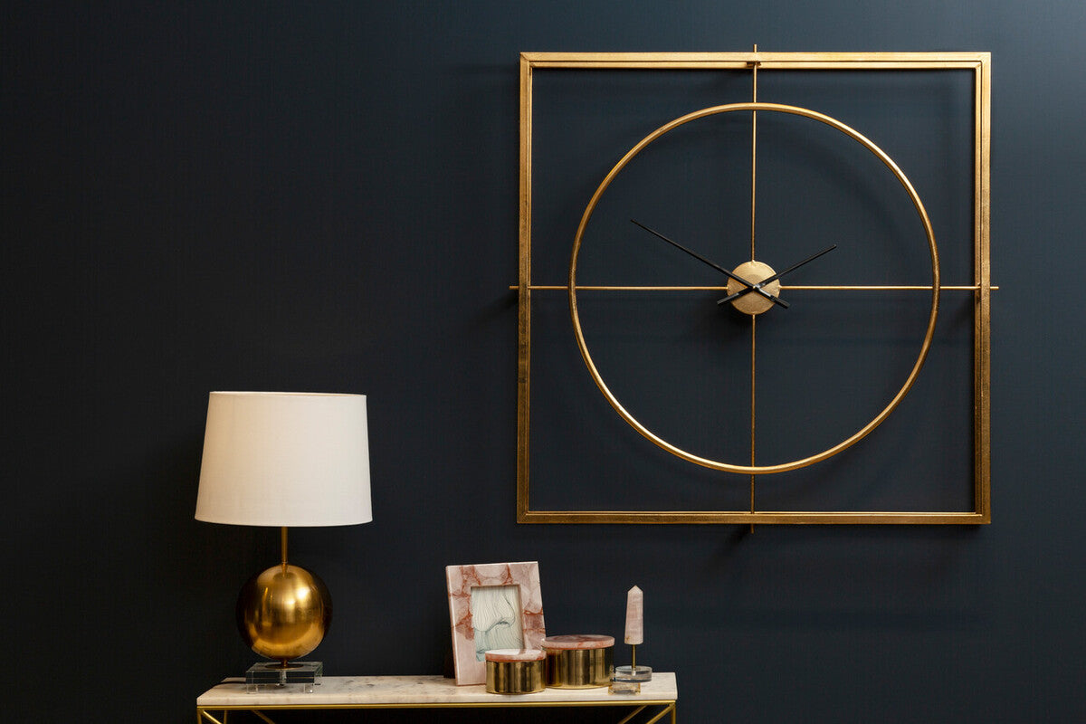 Gold-toned trinity metal wall clock with geometric design, minimalist circular face, and slender hands for stylish decor