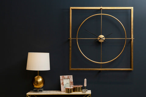 Gold-toned trinity metal wall clock with geometric design, minimalist circular face, and slender hands for stylish decor