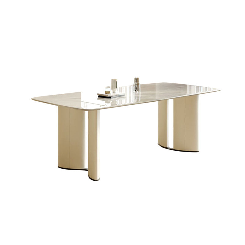 Cream-colored trish dining table with sleek reflective glass top and marble cylindrical legs for modern dining