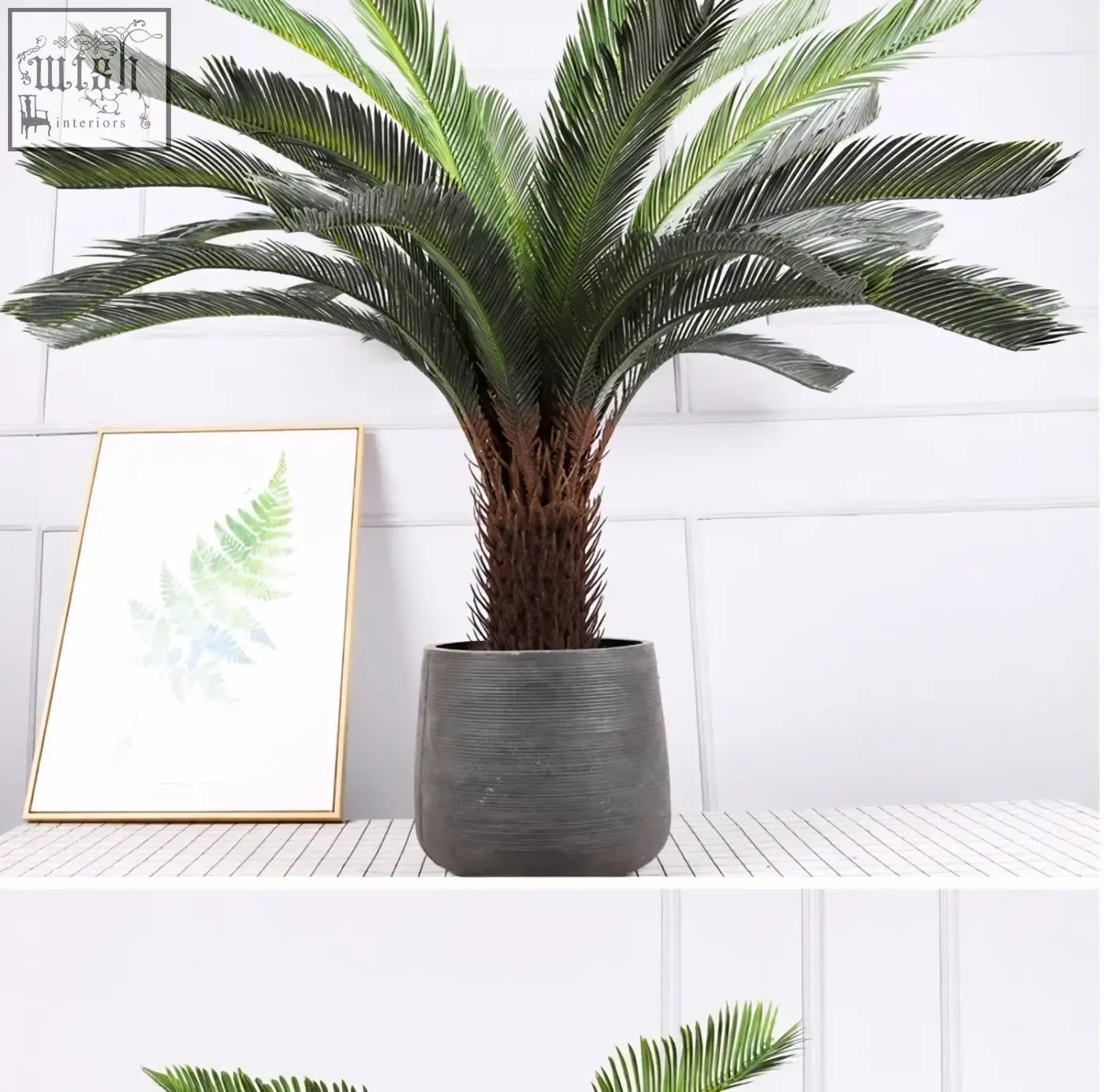 Tall tropical artificial palm tree with lush green plastic palm leaves in dark gray ribbed ceramic pot for indoor decor