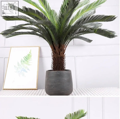 Tall tropical artificial palm tree with lush green plastic palm leaves in dark gray ribbed ceramic pot for indoor decor
