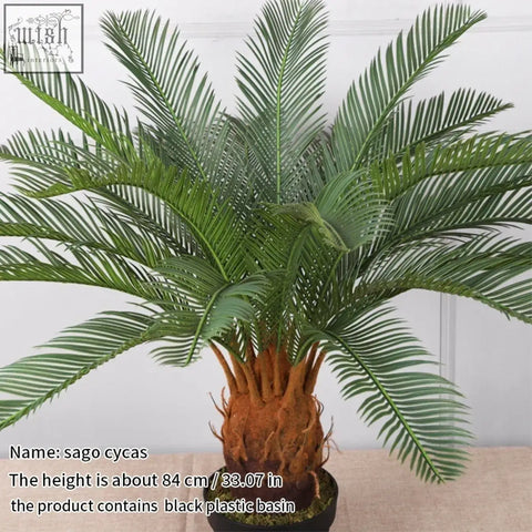A tropical artificial palm tree with lush green plastic palm leaves and a textured brown trunk in a black pot