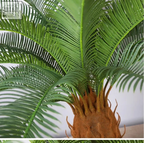 A lush tropical artificial palm tree with green plastic palm leaves and a textured brown trunk for indoor decor