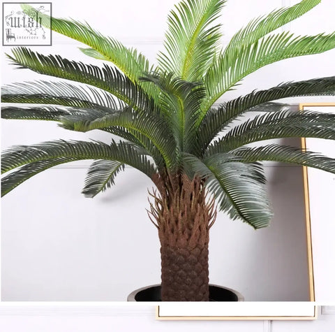A lush tropical artificial palm tree with textured brown trunk and plastic palm leaves for home or office decor