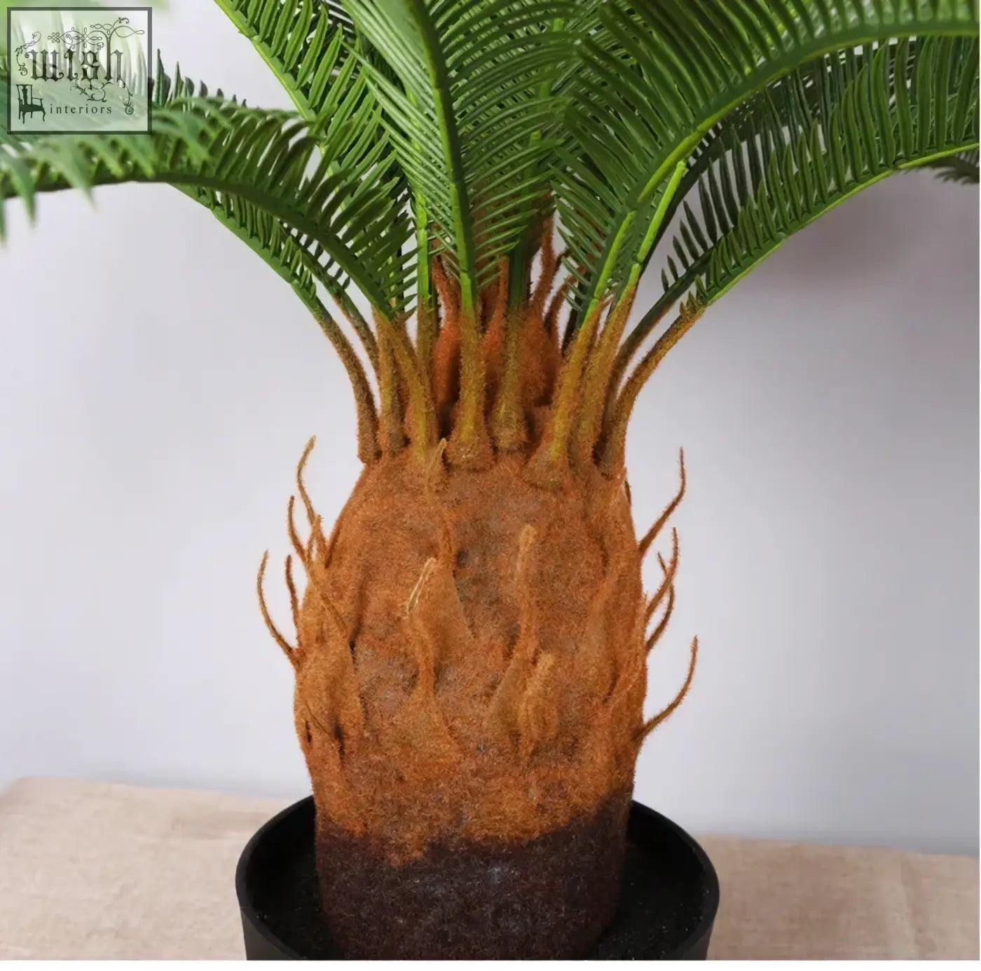 A realistic tropical artificial palm with vibrant green plastic palm leaves and a textured brownish-orange trunk perfect for home or office decor