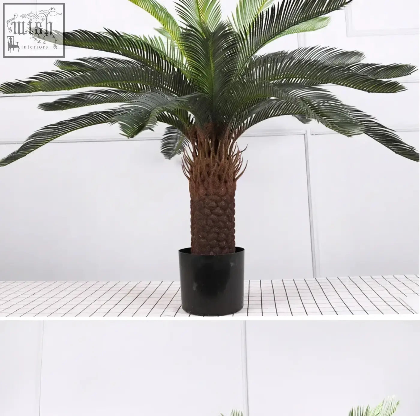 Realistic artificial palm tree with dark green plastic palm leaves and textured trunk in sleek black pot for decor