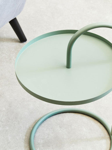 A minimalist trosa green hanging top side table with a smooth metal mint green circular tray and curved handle