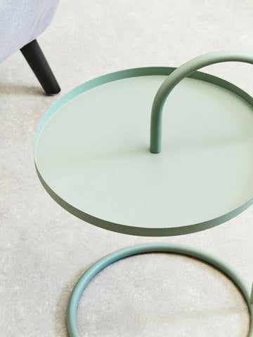 A minimalist trosa green hanging top side table with a smooth metal mint green circular tray and curved handle