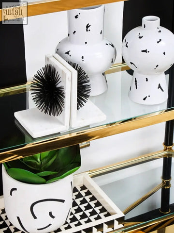 White ceramic tundra black planter with curved black lines and abstract splatter patterns on a glass shelf