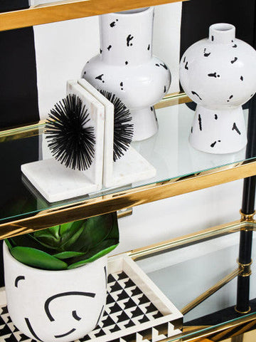 White ceramic small vase with black abstract splatter patterns on a glass shelf black small vase design