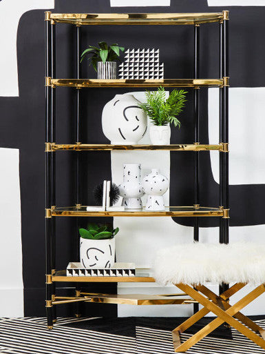 Gold-framed glass shelving unit with black vertical supports displaying a tundra white and black small vase