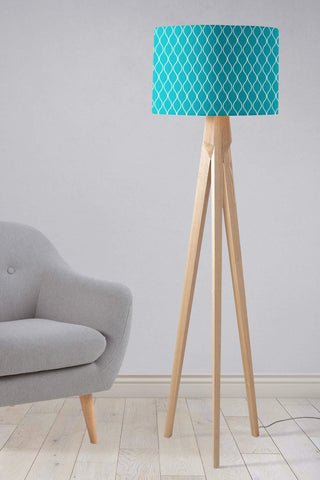 Teal table lamp with a white geometric design fabric lampshade on a light wood tripod base
