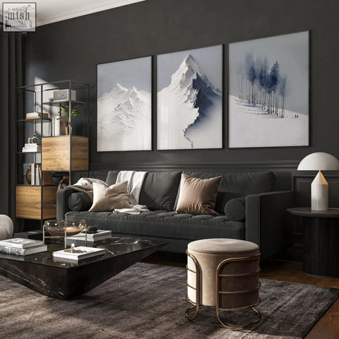 Dark gray upholstered sofa with beige taupe pillows in living room featuring mountain landscape scandi wall art set of 3